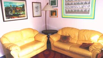 Una habitación con dos sofás de cuero amarillo, una mesita redonda y una lámpara.