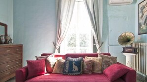 A room with a red sofa, a wooden dresser, a radiator, and a gramophone. - Angeli dell'Osanna B&B (Nardò)