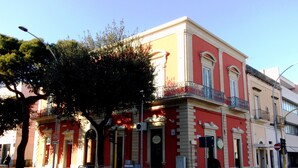 A red building with a balcony, a tree in front, and a 'No Parking' sign. - Angeli dell'Osanna B&B (Nardò)