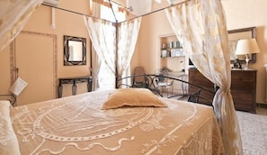 Une chambre à coucher avec un lit à baldaquin, une table de chevet, une chaise, une commode et un miroir.