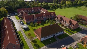 A residential area with multiple brick buildings, a parking lot, and a green field.
