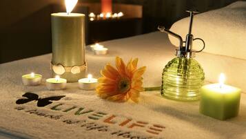 A room with a massage table, candles, and a flower.