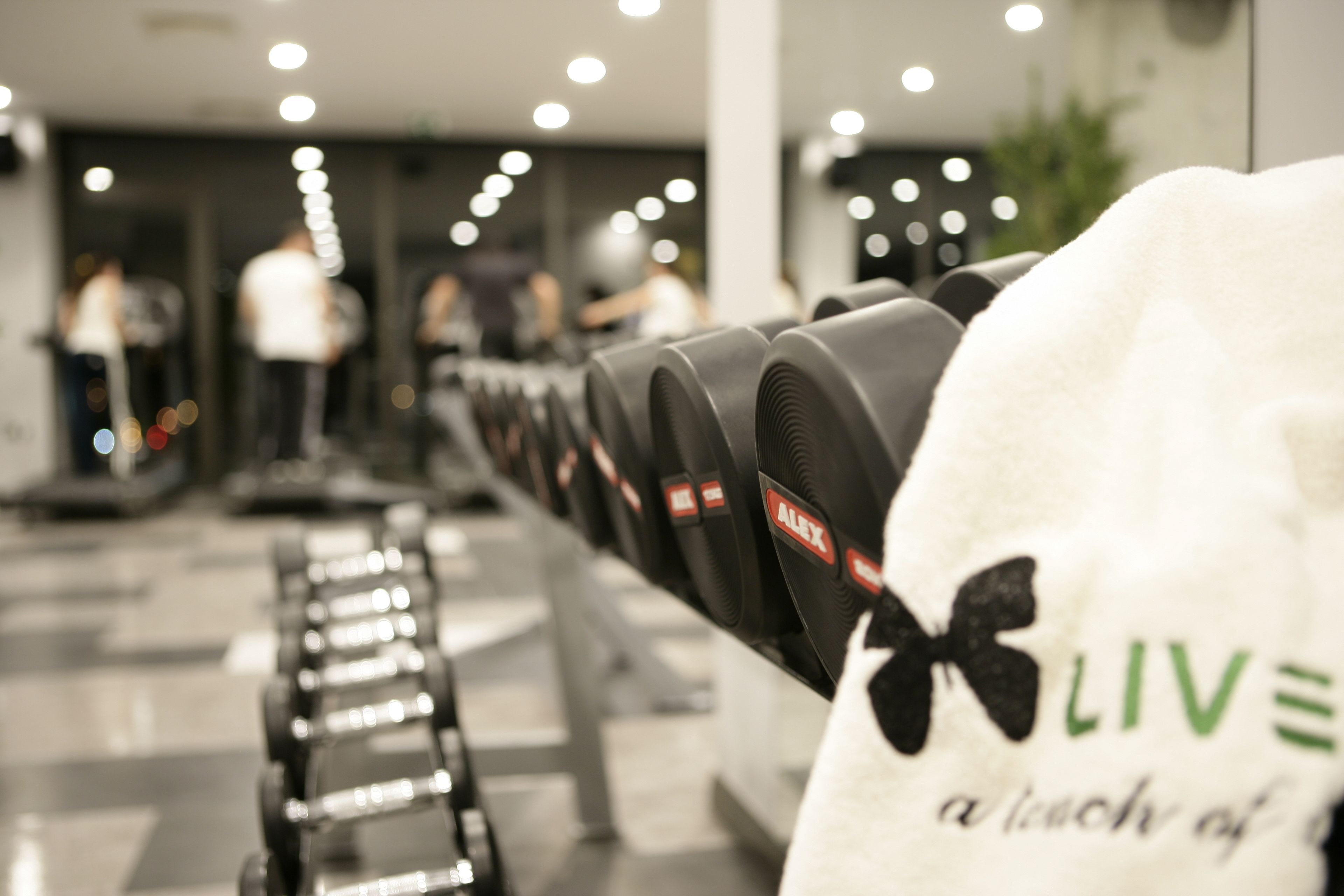 A row of black exercise equipment in a gym with a white towel hanging on the side.