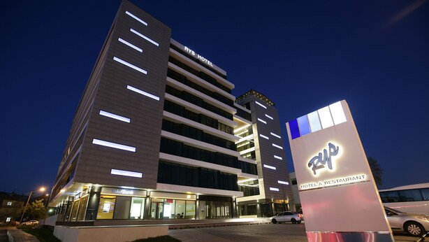 Un edificio moderno de hotel con un cartel que indica 'RYS Hotel' y 'KIF Bank' en la planta baja.