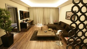 Una sala de estar moderna con una mesa de centro de madera, un sofá, un televisor y una planta decorativa.