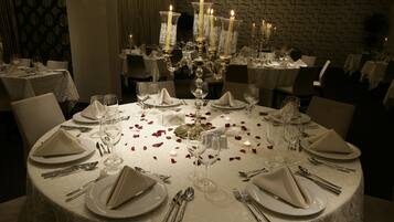 A formal dining room with round tables, white tablecloths, and candle-lit candelabras.