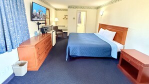 A hotel room with a bed, a desk, a television, and a waste bin. - Vaughan Inn (Vaughan)