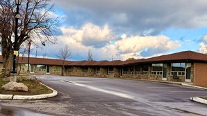 A building with a stone facade and a flat roof, featuring large windows and a parking lot in front. - Vaughan Inn (Vaughan)