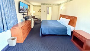A hotel room with a bed, a desk, a television, a chair, and a waste bin. - Vaughan Inn (Vaughan)