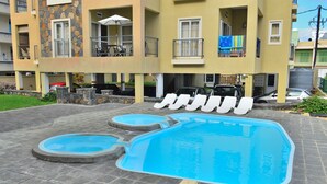 A swimming pool with a stone border and a small circular pool.