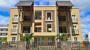 A multi-story building with balconies, stone accents, and a gated entrance.