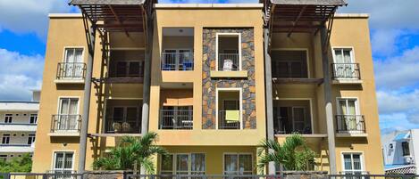 A multi-story building with balconies, stone accents, and a gated entrance.