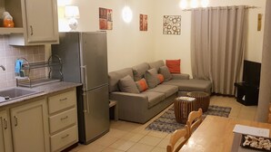 A compact living space with a kitchenette, a sofa, a dining table, and a TV.