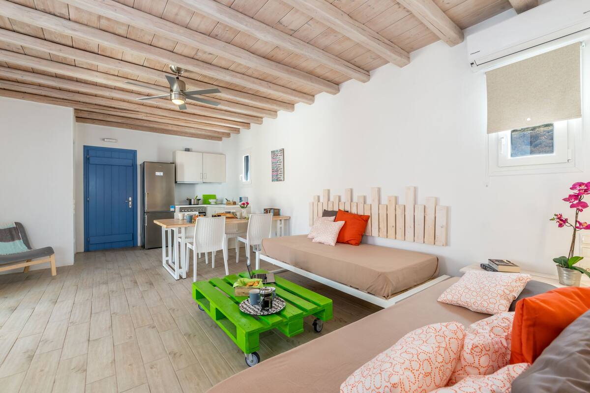 Un espacio habitable moderno y compacto, con kitchenette, comedor y dormitorio con cama y zona de estar.