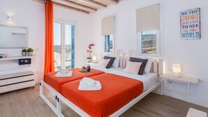 A hotel room with two beds, a large window with a view, a ceiling fan, and a motivational quote on the wall. - Electra Village (Mykonos)