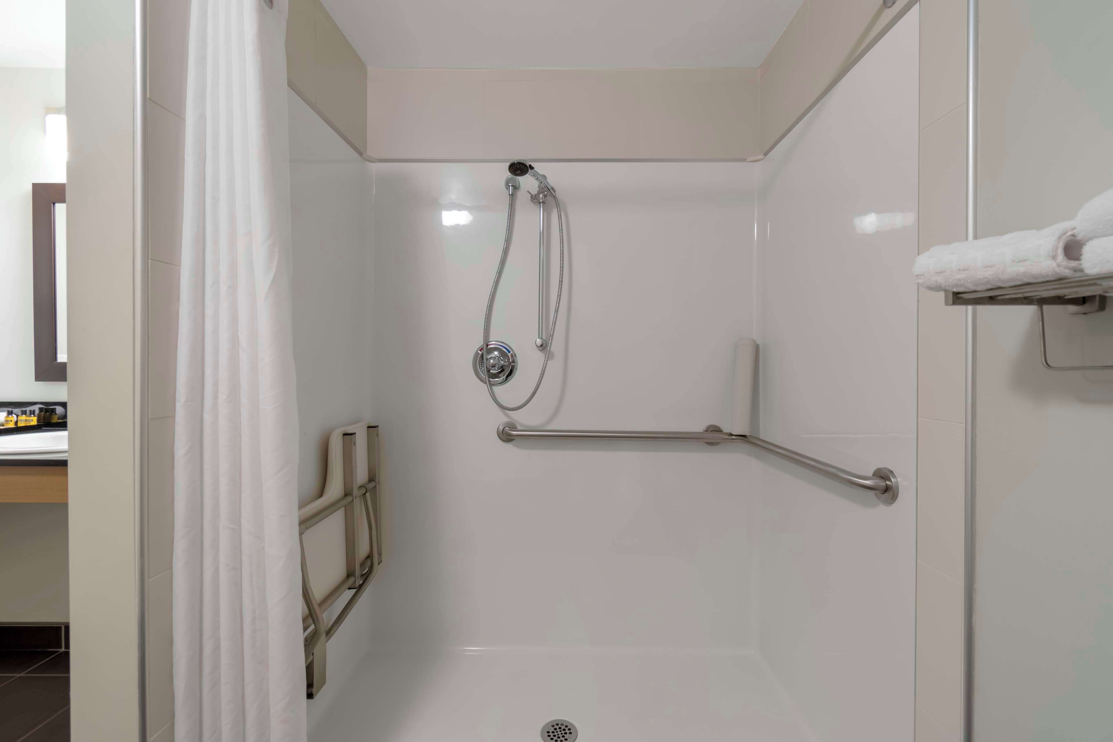 A modern shower area with a grab bar, a showerhead, and a towel rack.