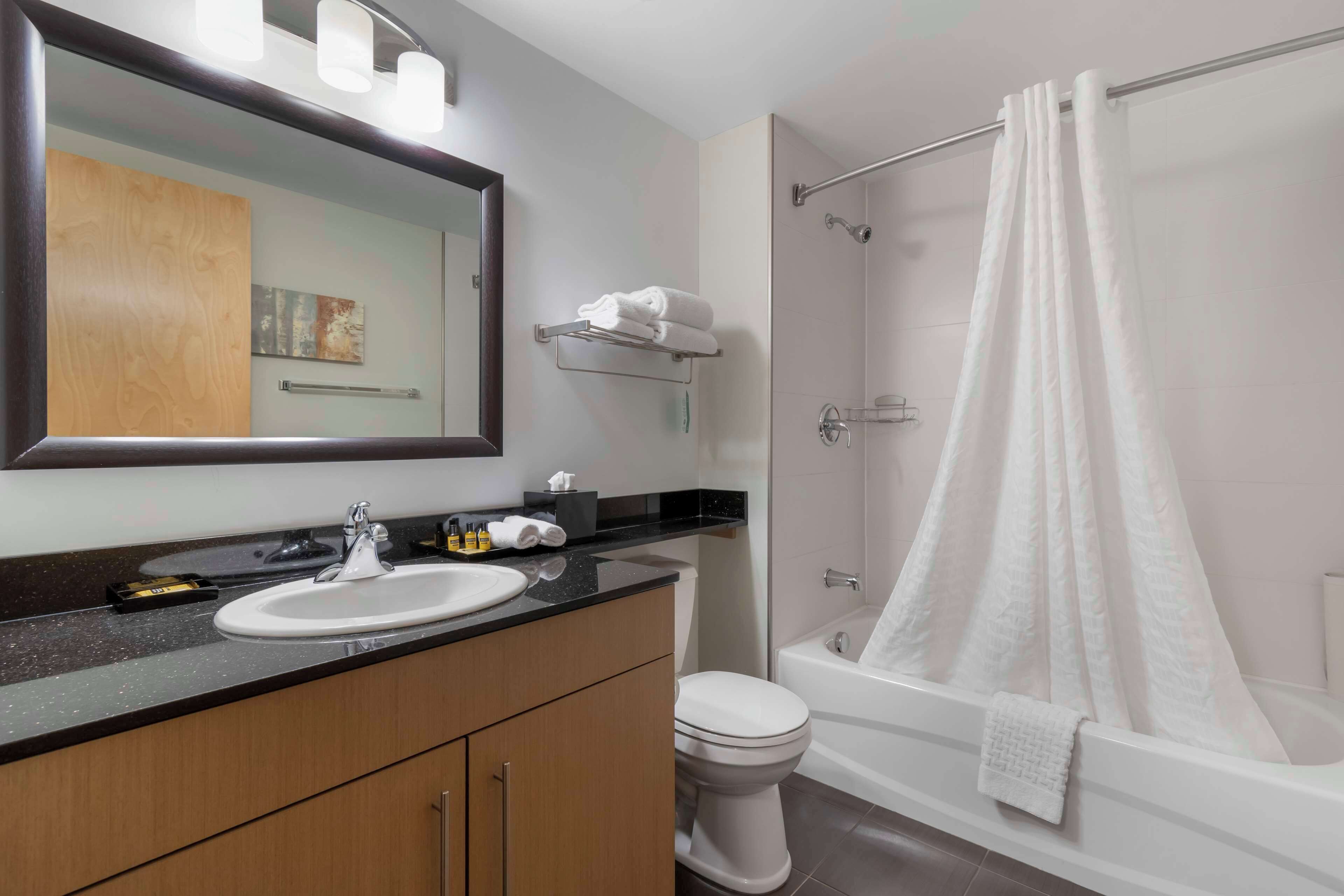 Un baño moderno con lavabo, espejo y ducha.