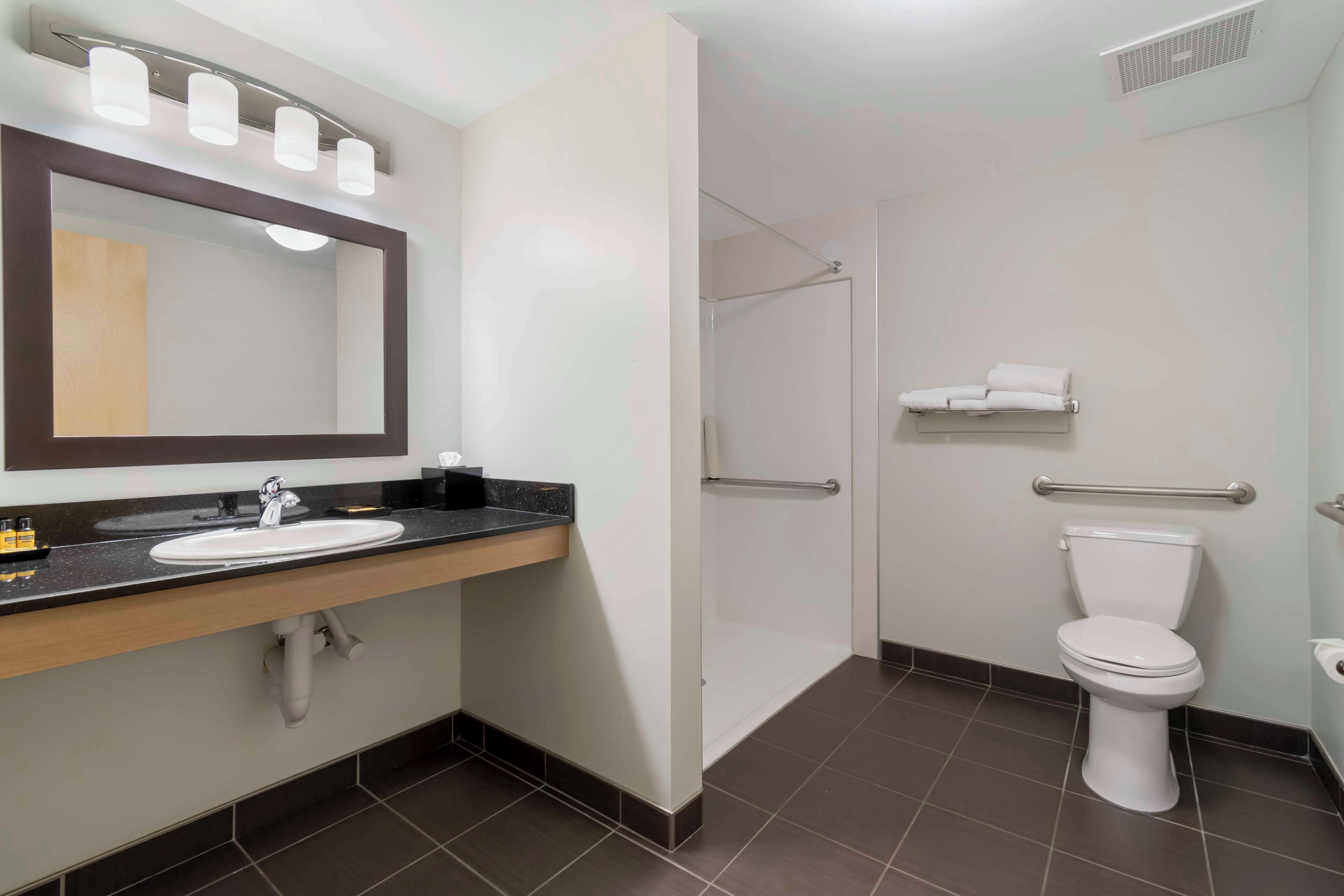 Une salle de bain moderne avec un lavabo, un miroir et des toilettes.