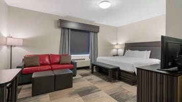 Una habitación de hotel con una cama, un sofá rojo, un escritorio y un televisor.