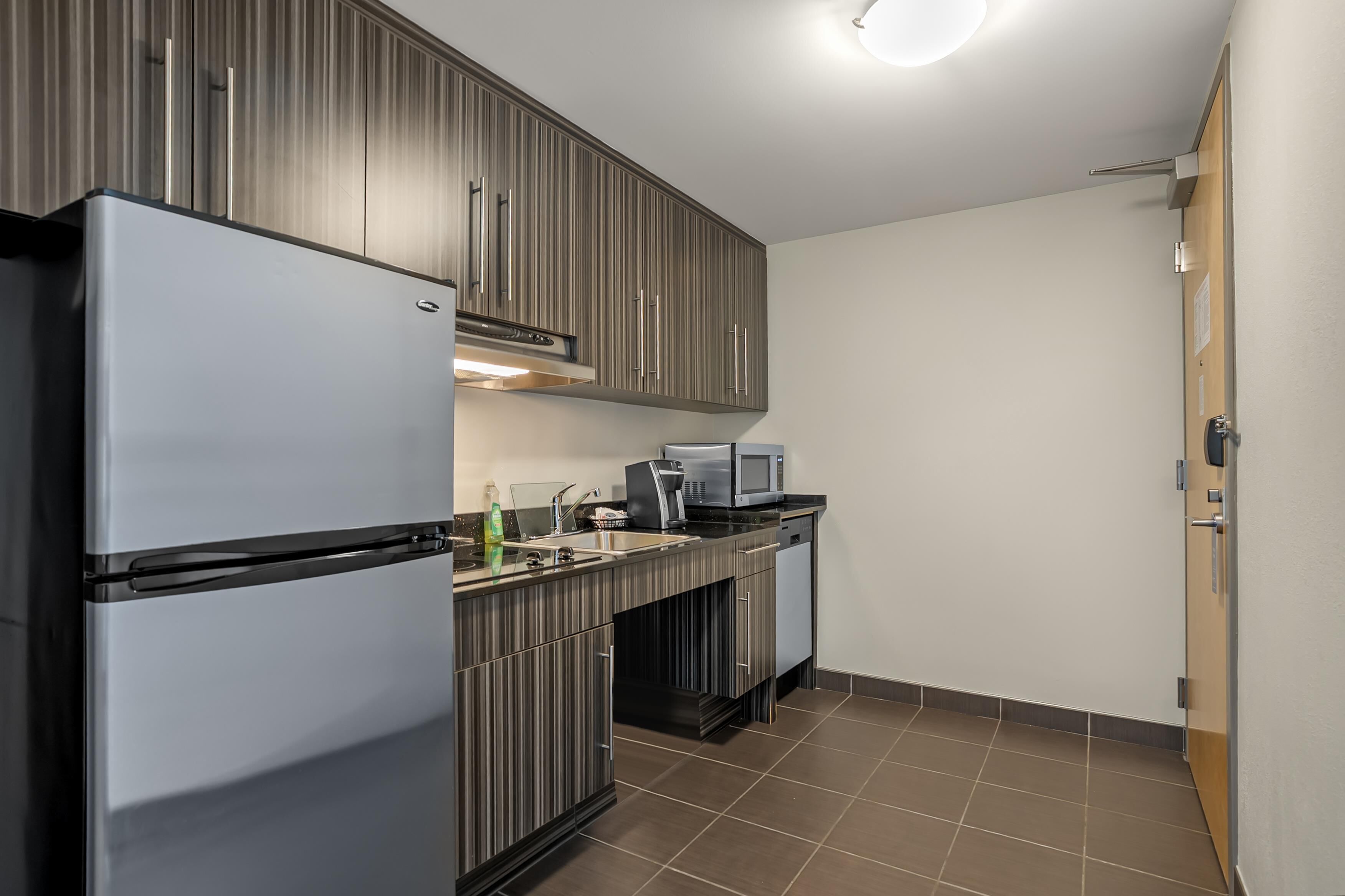 A compact kitchen with a refrigerator, microwave, and sink.