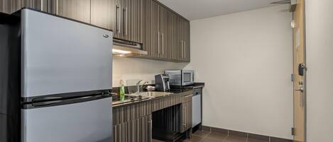 A compact kitchen with a refrigerator, microwave, and sink.