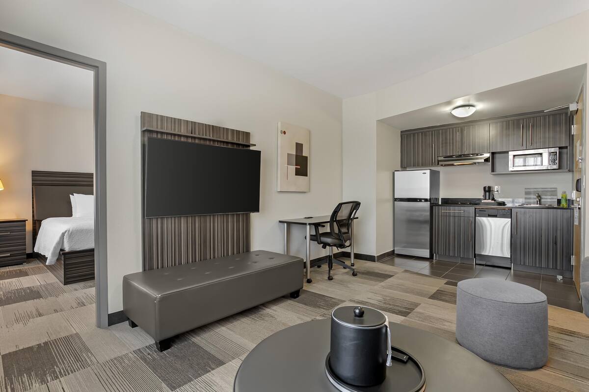 Una habitación de hotel moderna con cama, zona de estar, escritorio y kitchenette.