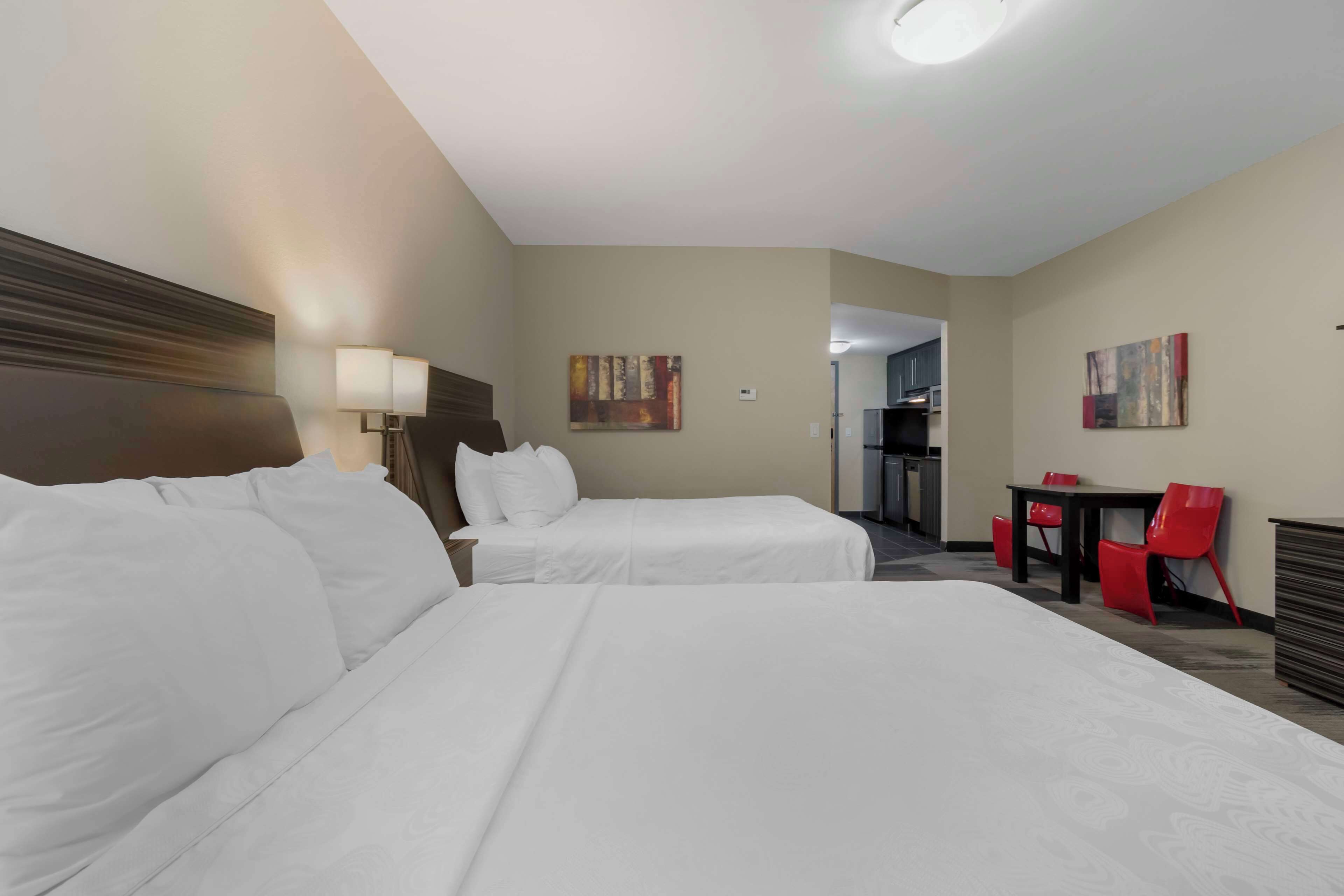 Une chambre d’hôtel avec deux lits, un bureau, une chaise et une lampe.