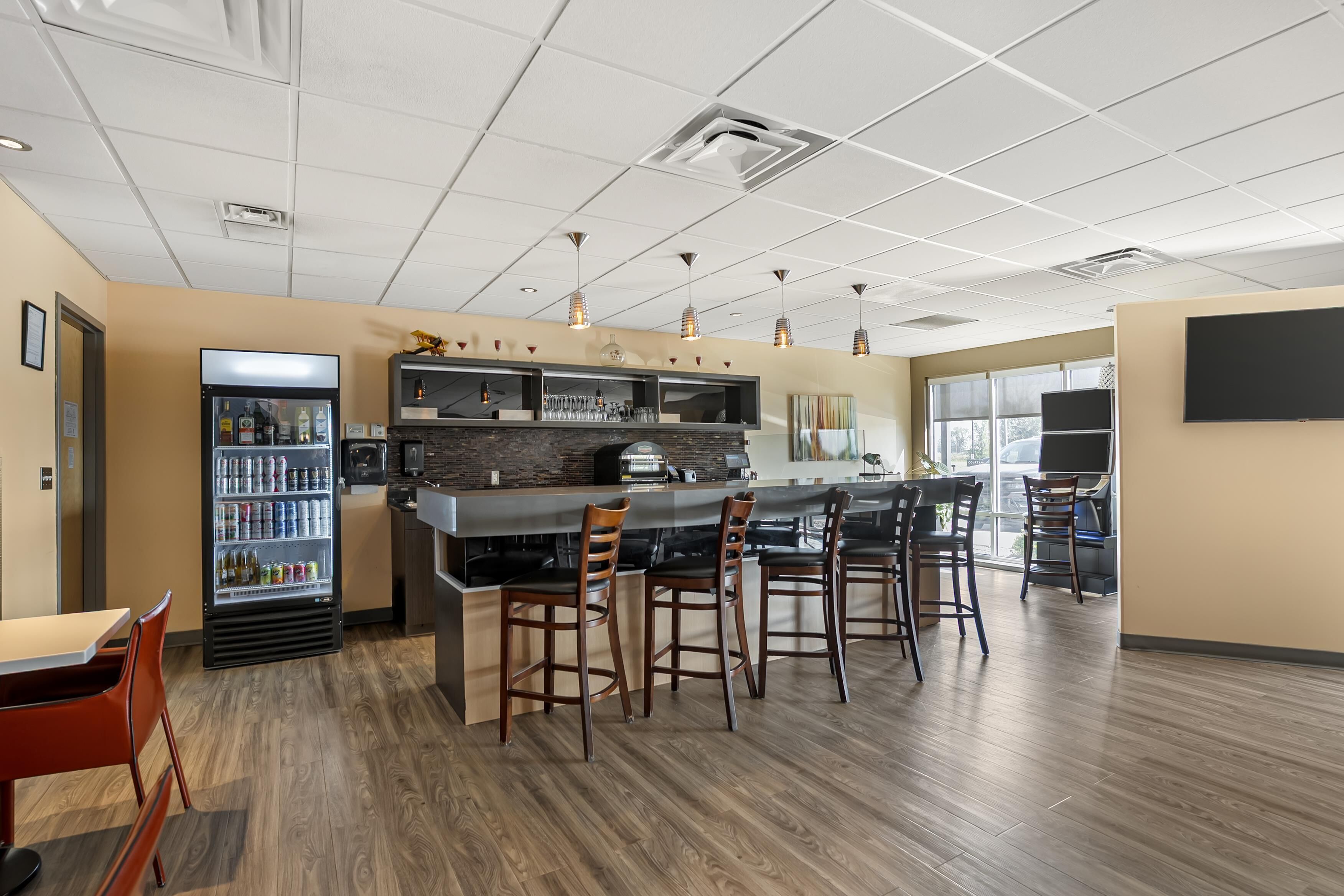 A modern bar area with a counter, stools, and a beverage dispenser.