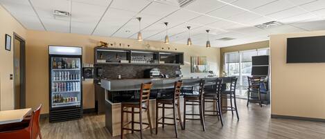 A modern bar area with a counter, stools, and a beverage dispenser.