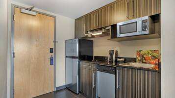 A modern kitchen with a refrigerator, dishwasher, microwave, and a wooden cabinet above the sink.