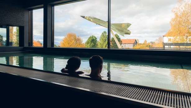 Une piscine intérieure dotée de grandes fenêtres donnant sur un aérodrome militaire.