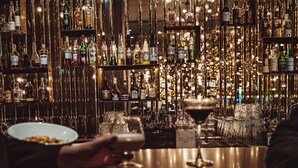 Un espace bar avec des étagères remplies de bouteilles d’alcool et de verres.