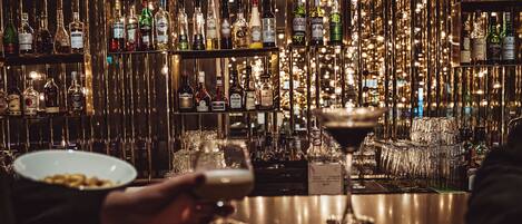 Una zona de bar con estantes llenos de botellas de licores y vasos.