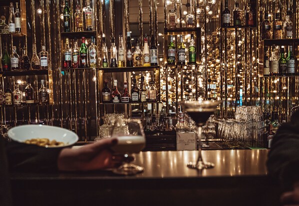 Un espace bar avec des étagères remplies de bouteilles d’alcool et de verres.