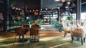 Un espace intérieur vaste et bien aménagé, avec différents types de sièges, notamment des tables et des chaises, ainsi qu’une variété de plantes.