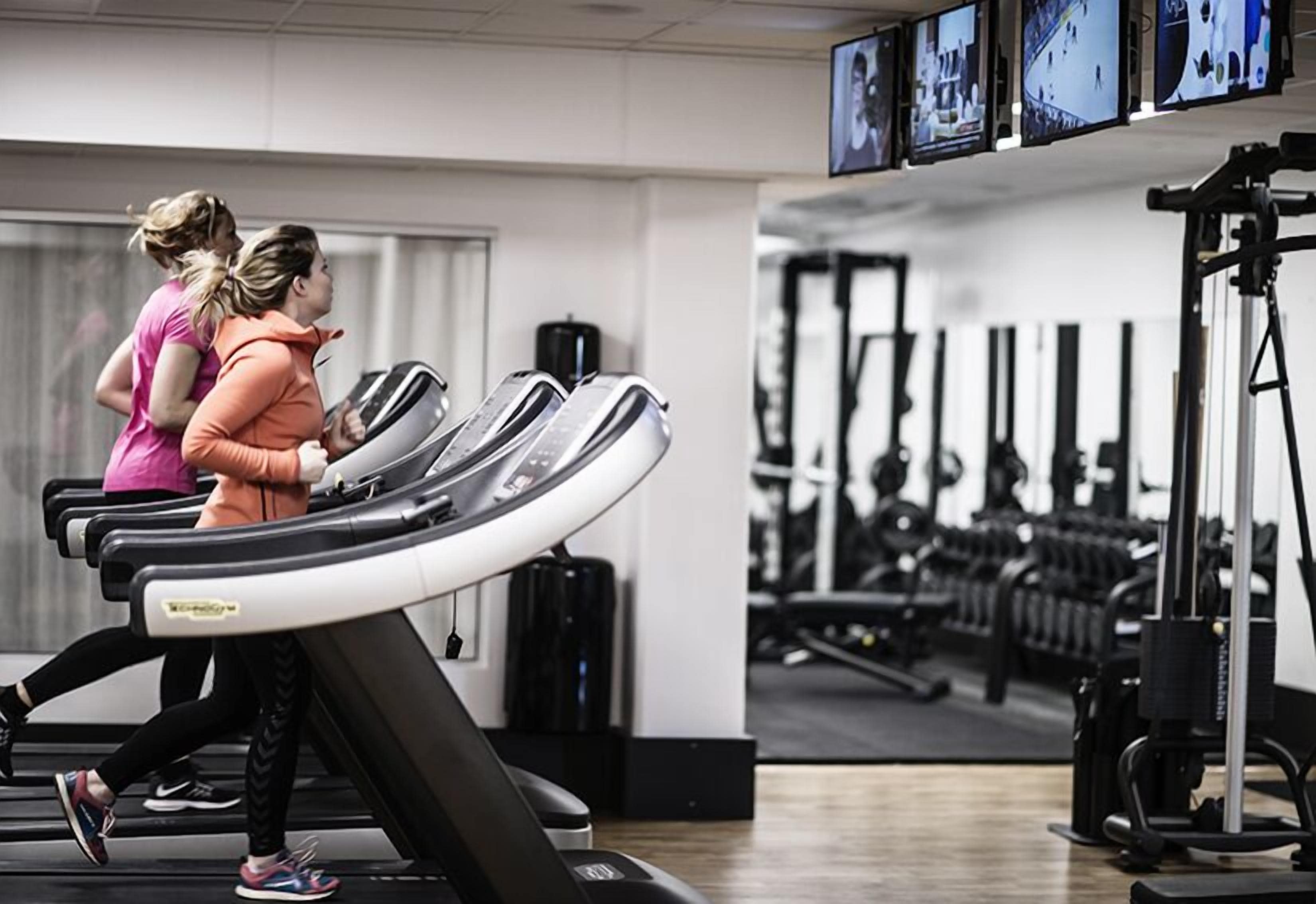 Een sportschool met loopbanden, krachtapparaten en fitnessapparatuur.