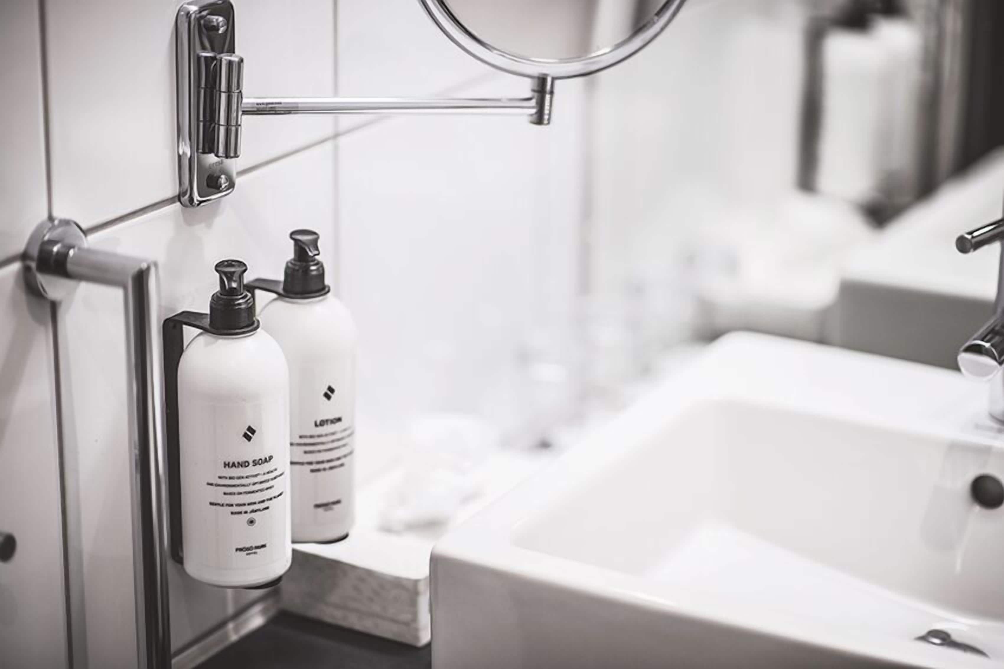 A bathroom with a white sink, a mirror, and two bottles of hand soap on a shelf.