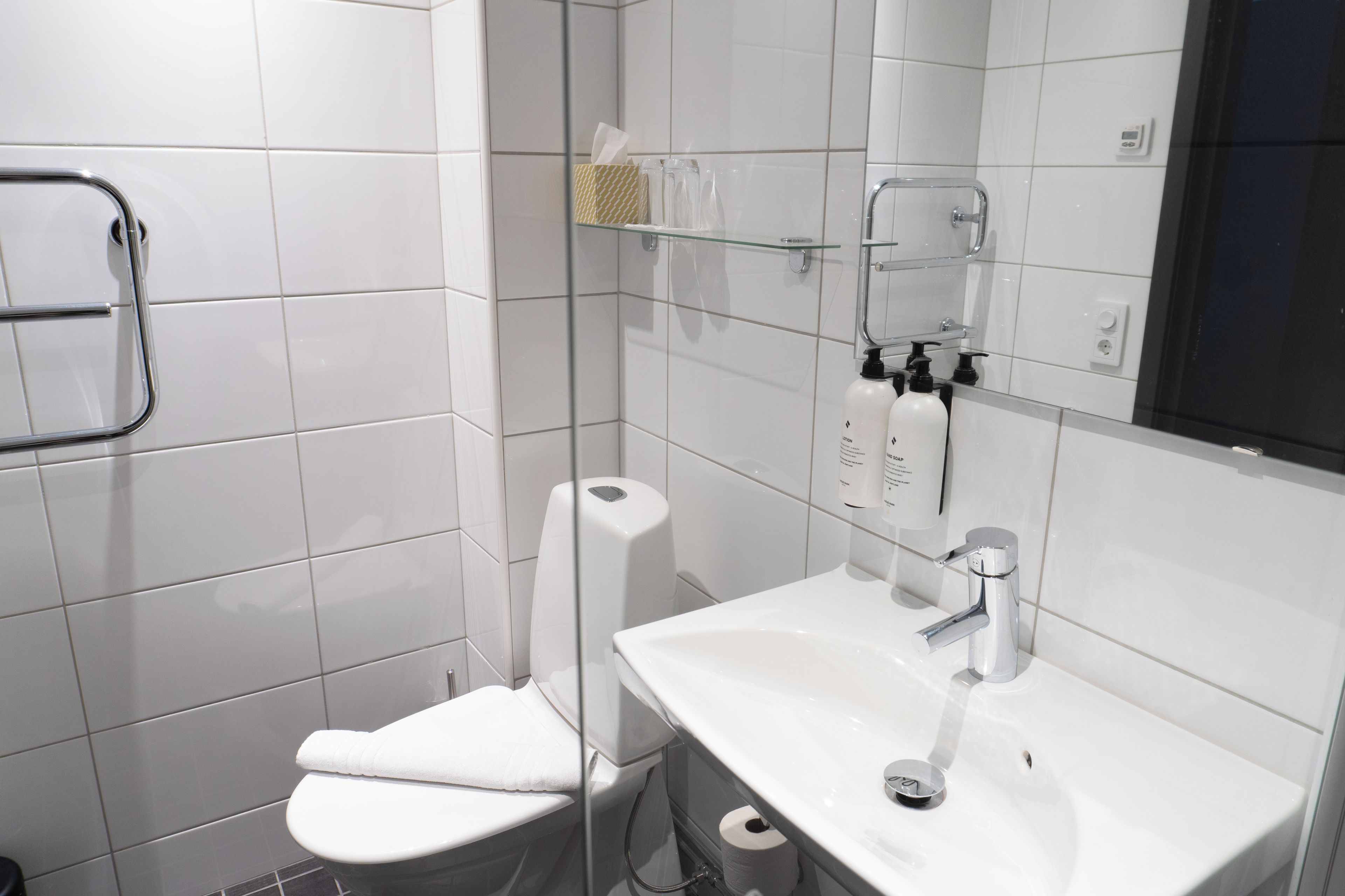Une salle de bain moderne équipée de toilettes, d’une douche à parois de verre et d’un lavabo avec un miroir.