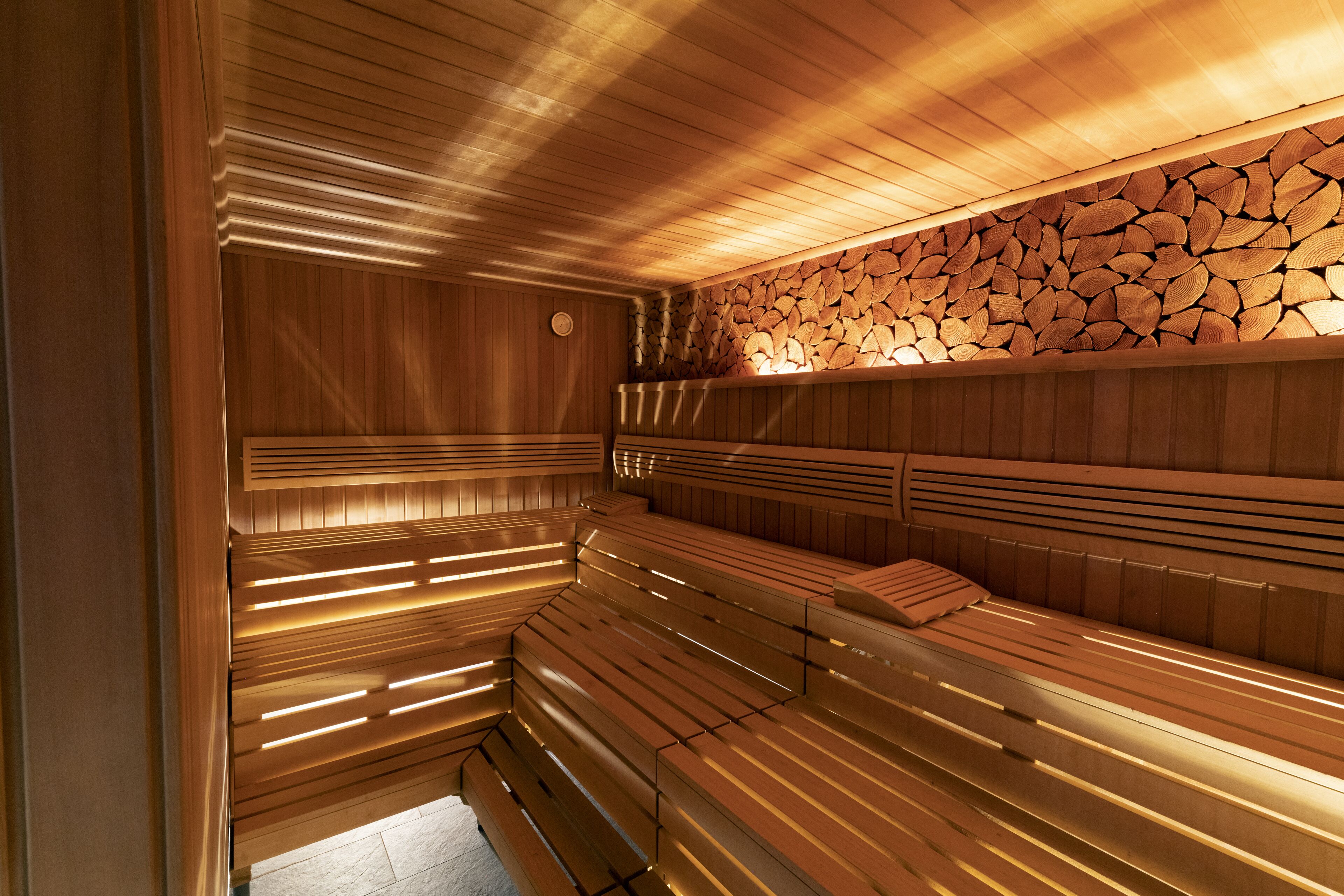 Un sauna avec des bancs en bois et un mur fait d’une pile de troncs.