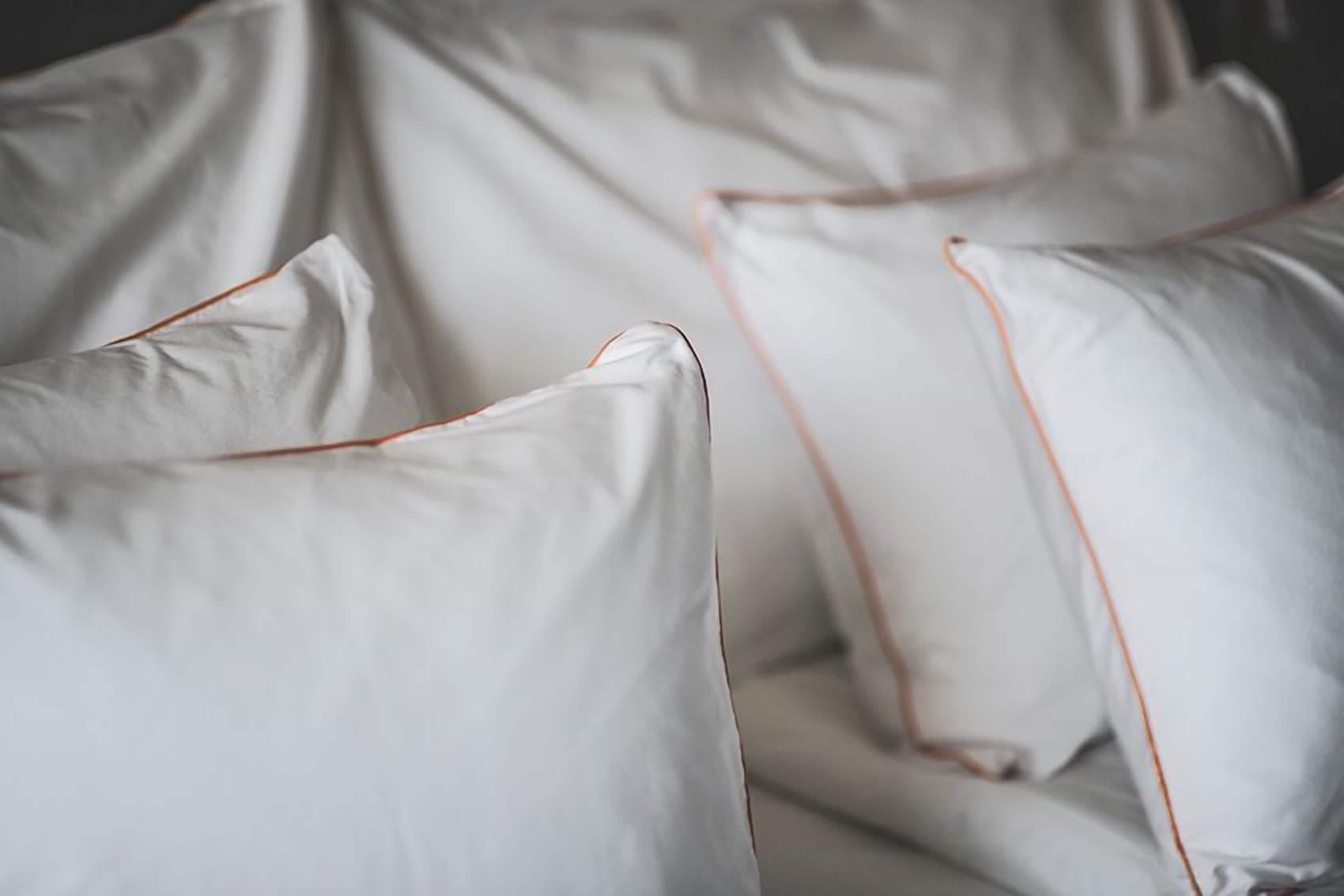 Un gros plan de coussins blancs ornés d’une bordure orange.