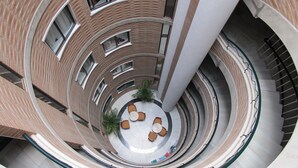 Un atrio de varios niveles con una zona de estar circular central, rodeado de muros de ladrillo y varios pisos.