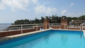Piscina con vistas al mar y un edificio al fondo.