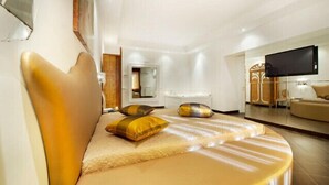 A modern hotel room with a curved sofa, a flat-screen TV, and a large mirror. - Hotel Il Quadrifoglio (Rome)