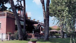A building with a brick facade, a covered walkway, and a well-maintained lawn. - Hotel Il Quadrifoglio (Rome)