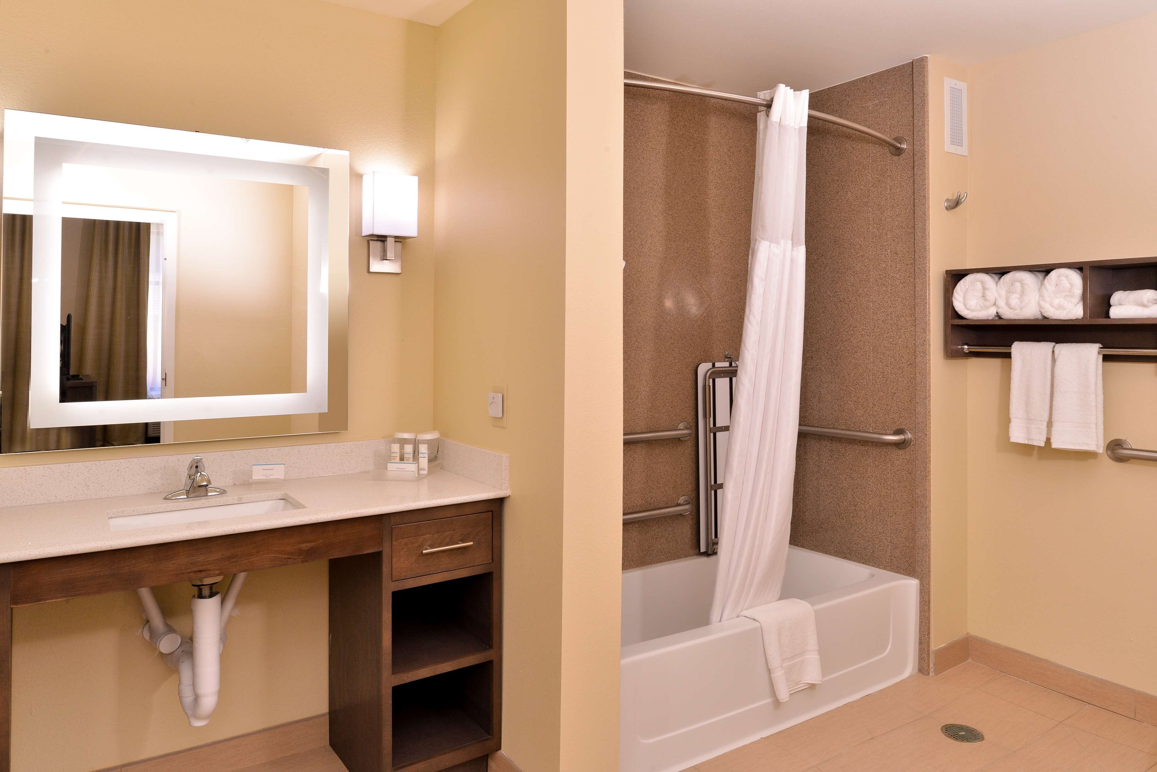 A bathroom with a sink, mirror, and shower area.