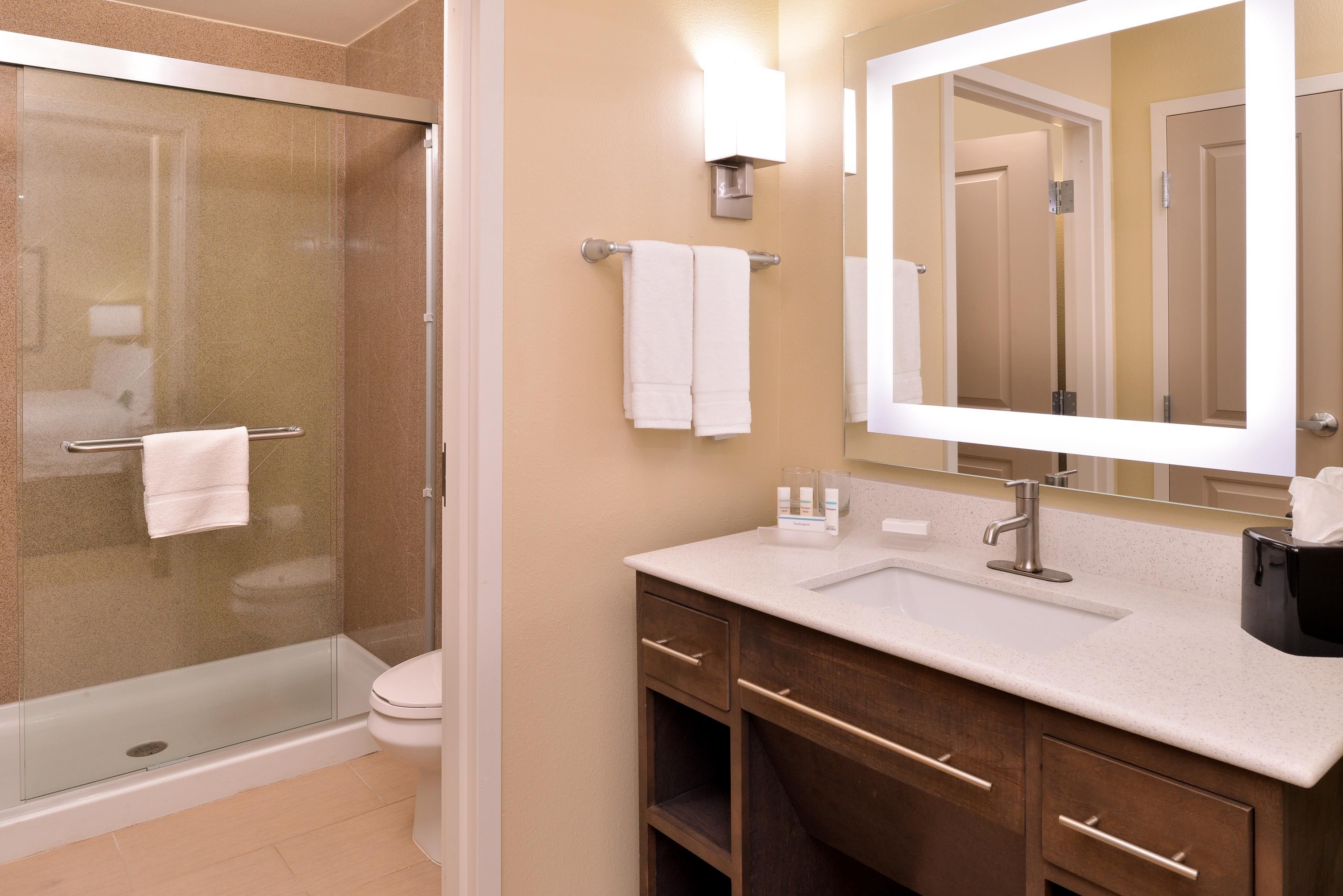 A bathroom with a glass-enclosed shower, a sink with a mirror, and a toilet.