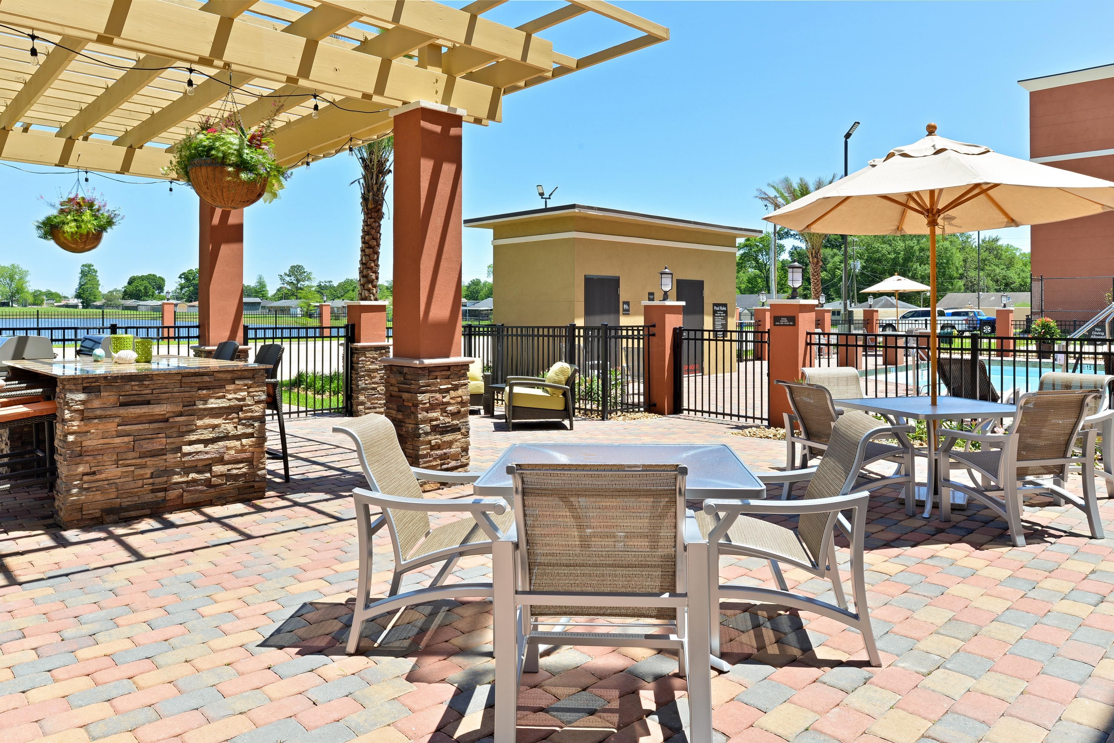 An outdoor patio area with tables and chairs, a pool, and a view of a body of water.