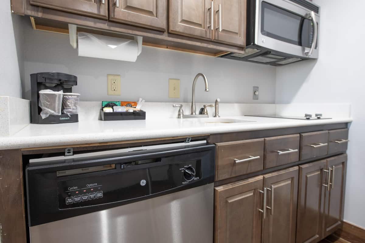 A kitchen with a dishwasher, a microwave, a sink, and wooden cabinets.