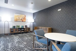 A modern lounge area with a sofa, a small table, and a decorative wall piece. - Homewood Suites Houma, La (Houma)