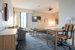 A hotel room with a bed, a desk, a chair, a TV, and a ceiling fan. - Homewood Suites Houma, La (Houma)